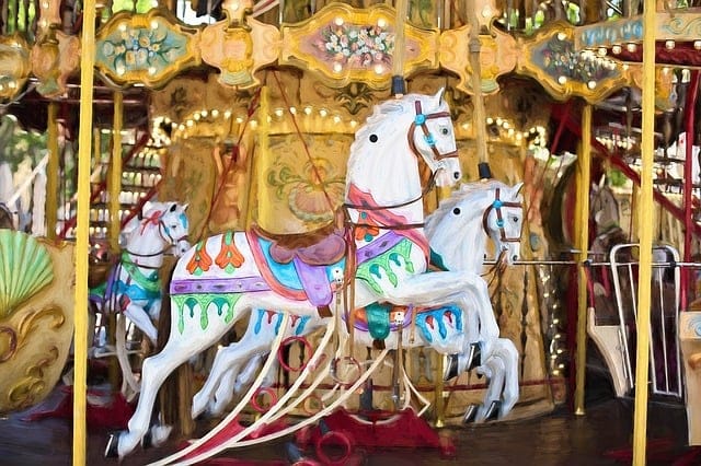 Photo of two white horses on a golden carousel